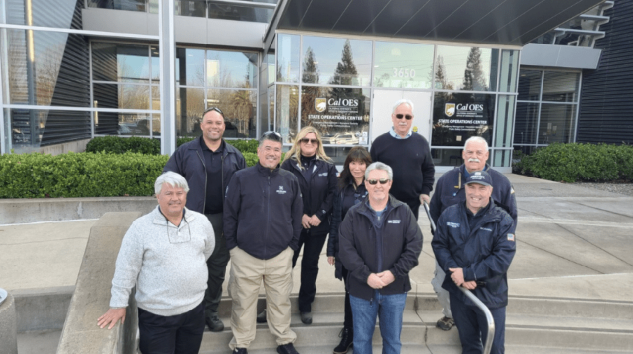 Group of individuals standing in front of a CAL OES building smiling at the camera