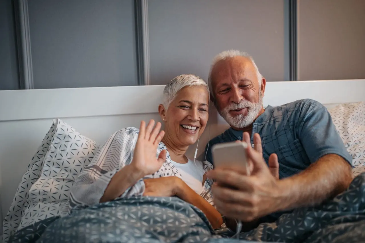 A couple looking at a phone and waving at the screen