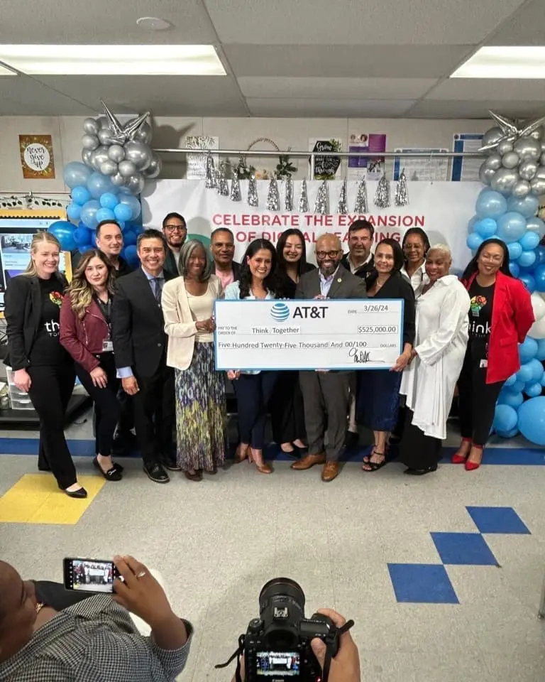 Classroom of individuals smiling while posing with a check from AT&T
