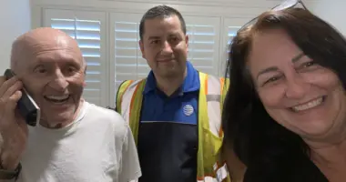 Two men, including one on a phone, and one woman taking a selfie