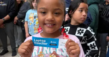 Young girl holding laptop voucher.