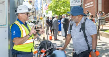 Man in PPE talking to man outside
