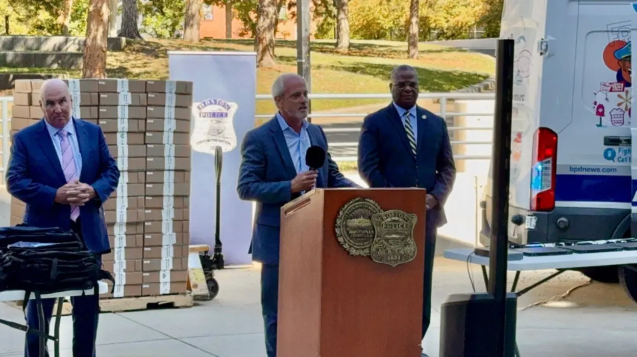 Three men standing behind a podium, one speaking.
