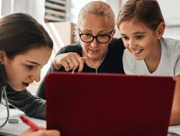 a mother with her two children all looking at a laptop screen