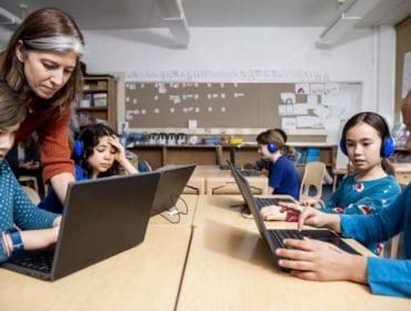 Teacher with children looking at laptop screen