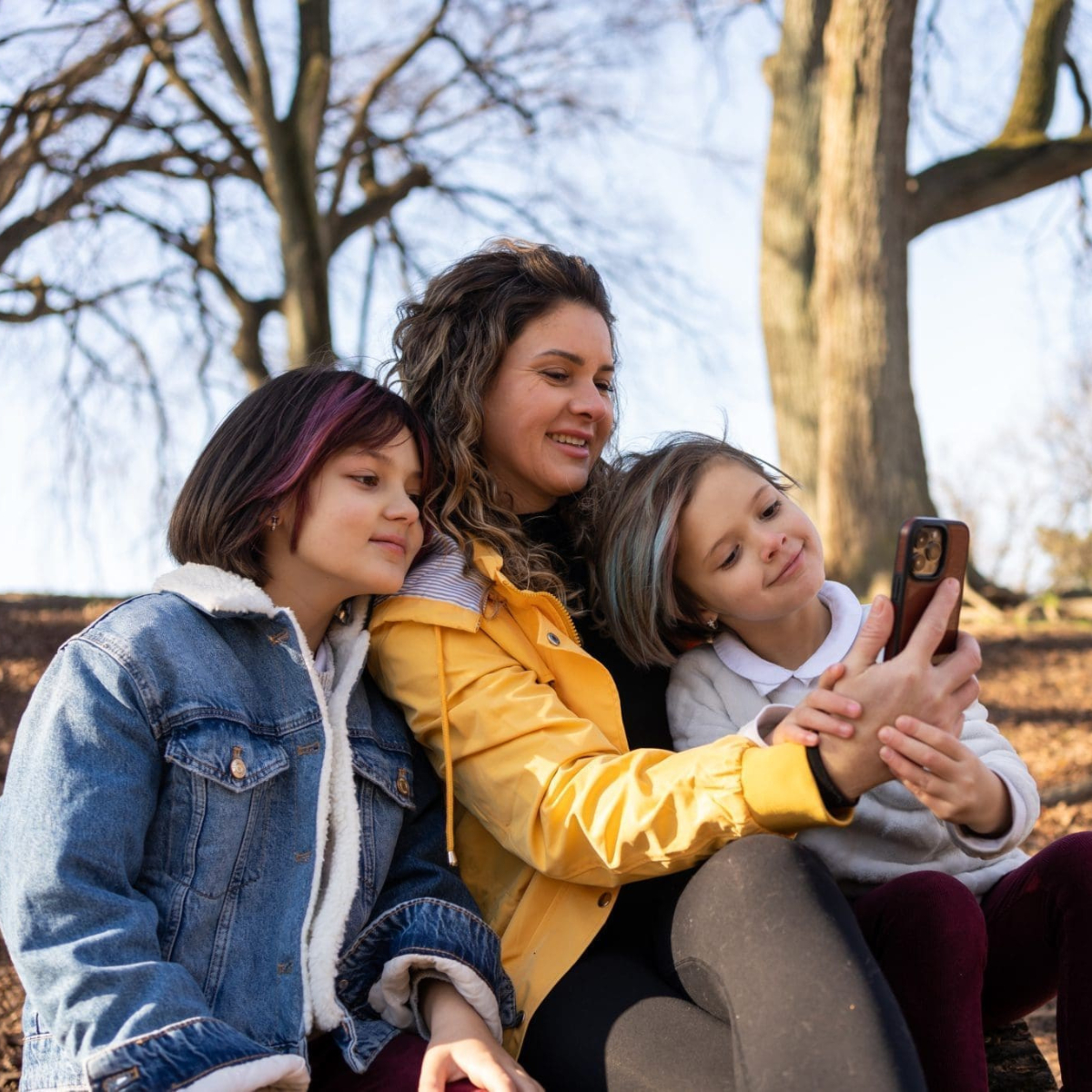 A woman and two kids looking at a phone