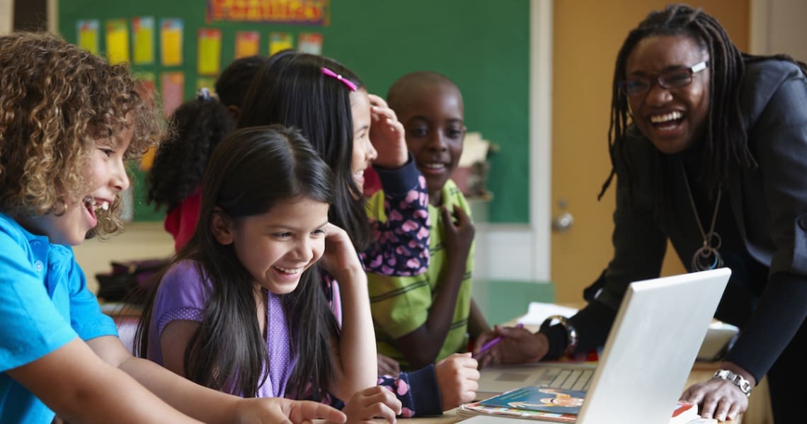 Image of 5 kids laughing along with a teacher