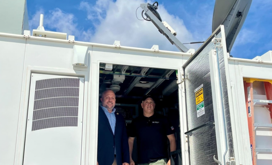 Two people standing in a truck with a satellite dish on top.