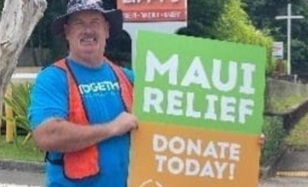 A man holding a Maui relief sign