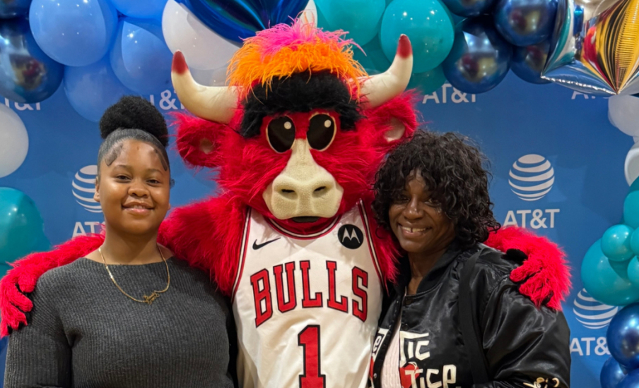 Two people standing with mascot
