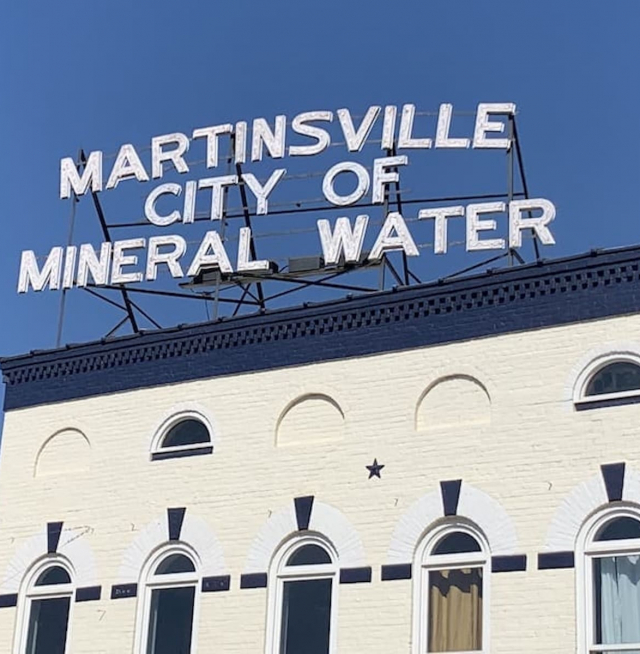 A sign on top of a building that says "Martinsville City of Mineral Water"
