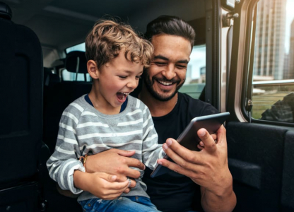 Man holding son smiling at phone