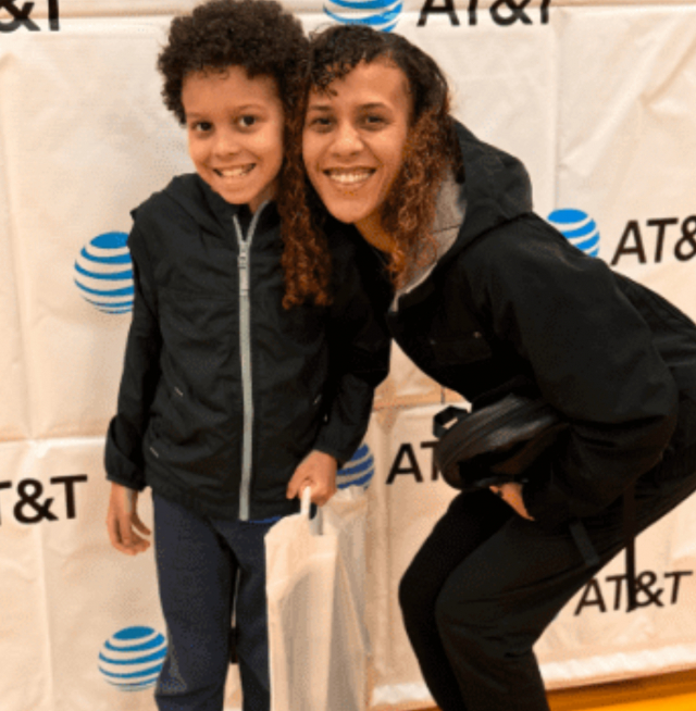 A mother and child smiling to the camera in front of an AT&T banner