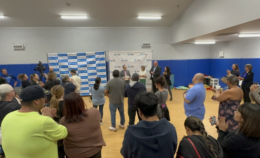 A group of people standing around 2 people who are speaking