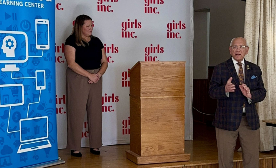 Two people talking on a stage in front of AT&T and Girls Inc. banners