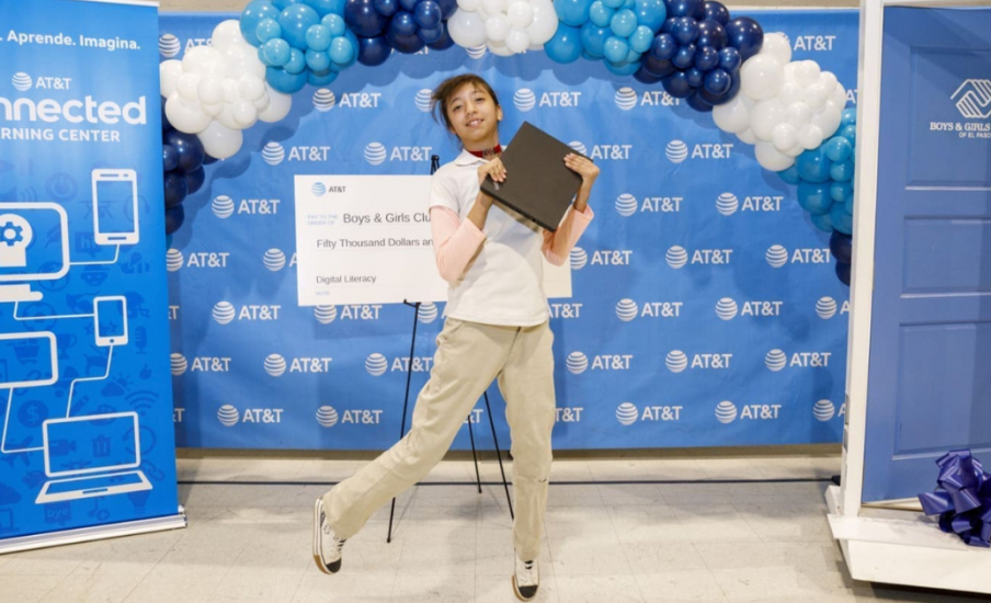 child standing in front of novelty check holding a laptop