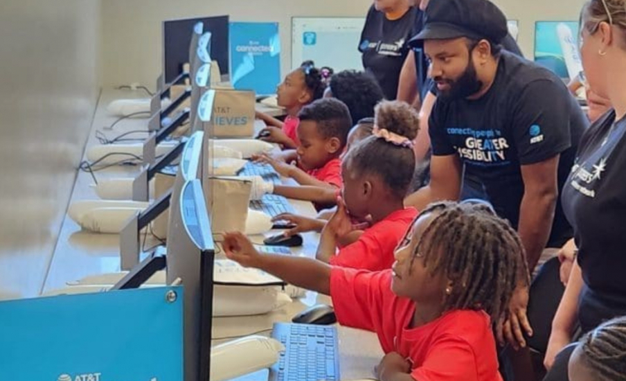 a group of children sitting at a row of computers