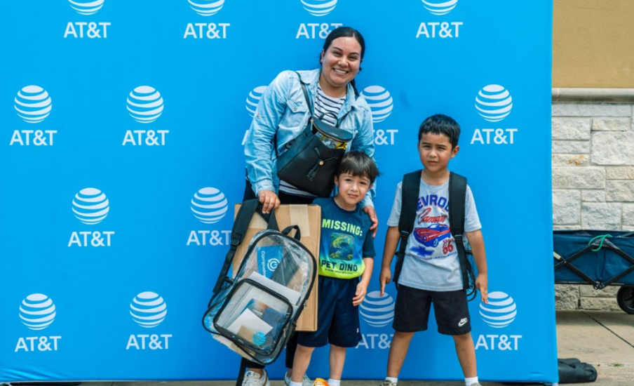 A family standing in front of an ATT background with their backpacks