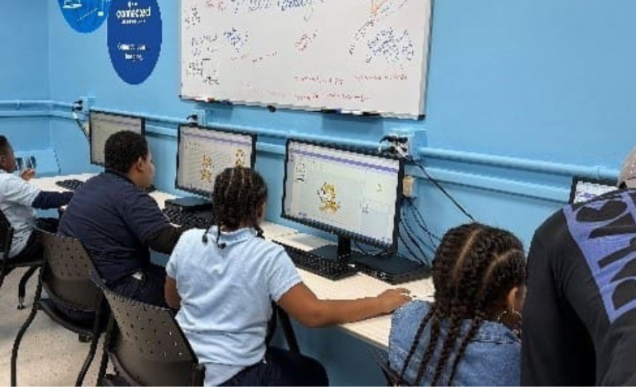 Three students sitting at computers in a computer lab.