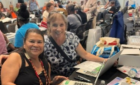 Two women smiling in front of laptops