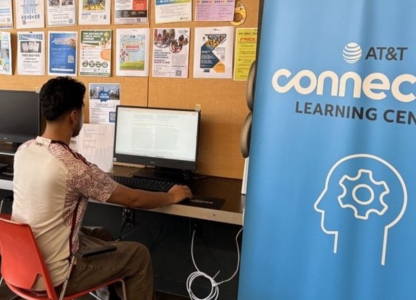 Person sitting at computer next to AT&T banner