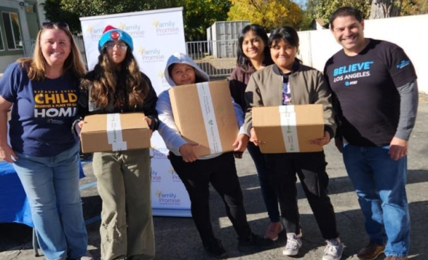 Individuals smiling while posing together with boxes with AT&T volunteers