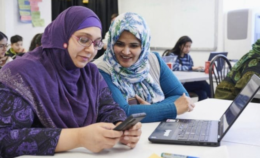 two women using a laptop and cell phone