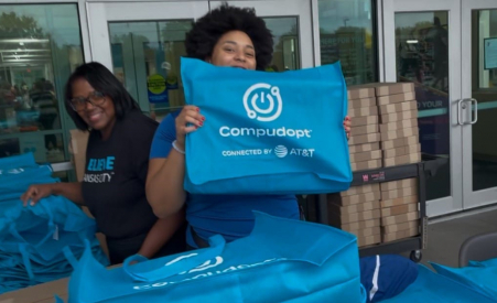 A person holding up a bag that says "compudopt connected by AT&T" on it.