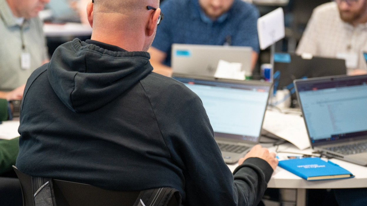 people sitting at laptops around a desk