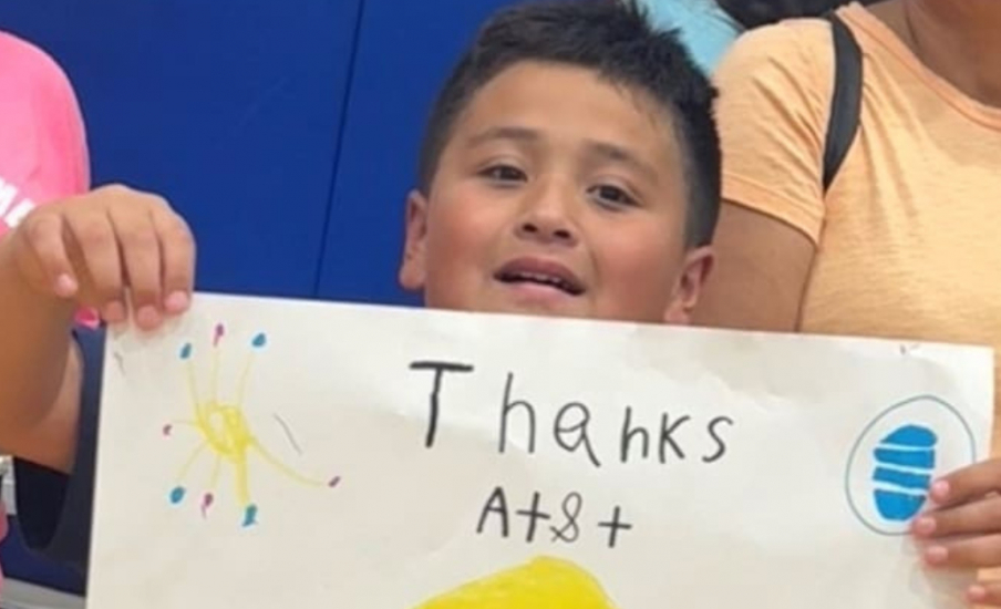 child holding up a handwritten sign that says "Thanks AT&T"