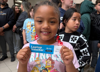Young girl holding laptop voucher.