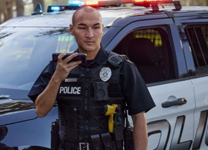 Police officer standing in front of police car on phone