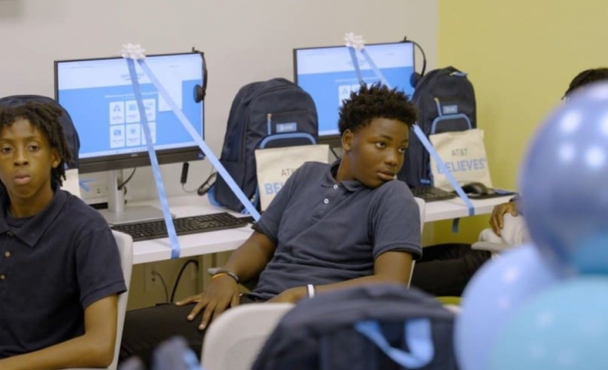 Children turning around away from computers in a computer lab, presumably listening to someone talk.