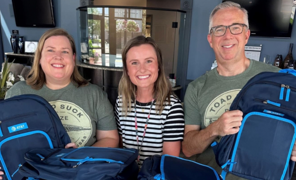 Group of 3 people holding AT&T branded backpacks to hand out