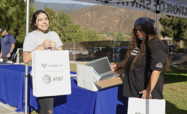Two people holding humani-t and AT&T bags