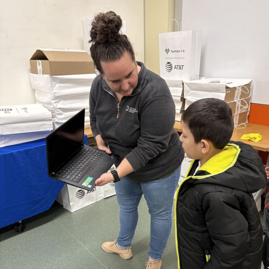 Woman handing child a laptop