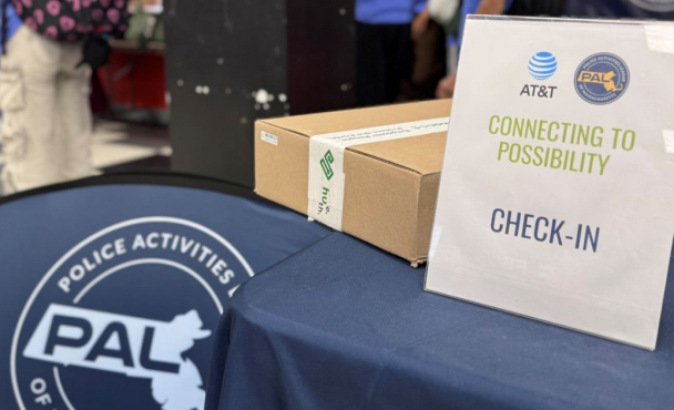 A table with a sign that reads "Connecting to Possibility Check-In". The sign has the AT&T and PAL of Massachusetts logo on it.