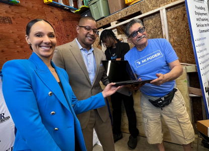 People smiling at laptop distribution event.