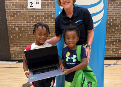 AT&T volunteer hands out laptops to children