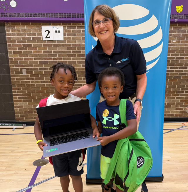 AT&T volunteer hands out laptops to children