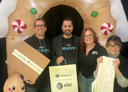 AT&T volunteers smiling with bags in front of a holiday-themed background
