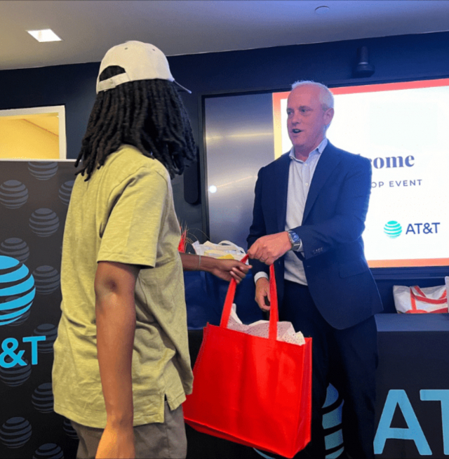 A man handing a student a laptop