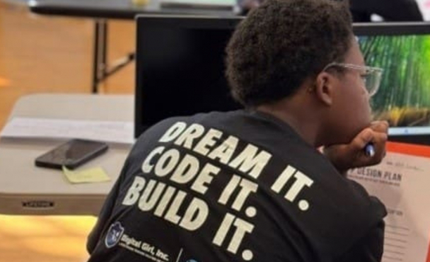 A teen with a shirt that says "Dream It. Code It. Build It." on the back