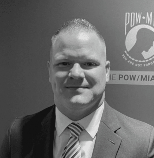 a man standing in front of a POW-MIA banner
