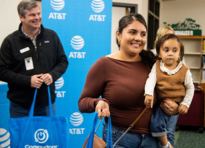 Woman holding child and laptop bag at device distribution