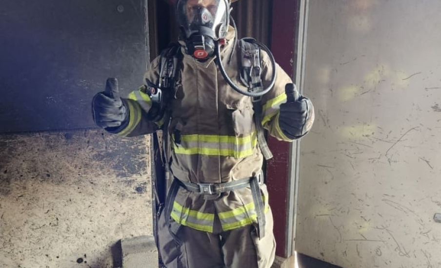 A person in a firefighter outfit giving two thumbs up