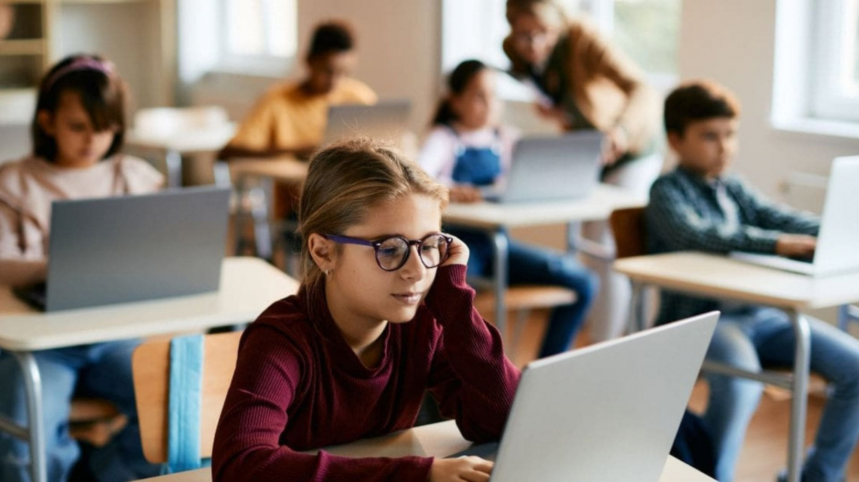 A group of kids on laptops in a classroom.