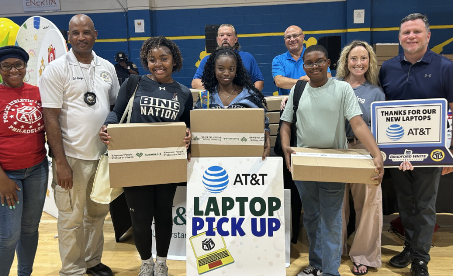 Students and adults holding laptop boxes at event.