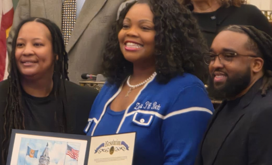 Three people smiling holding a declaration in a City Hall.