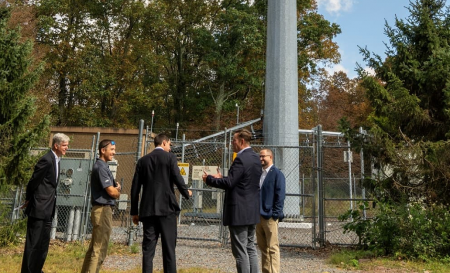 People talking to each other in front of a communications tower